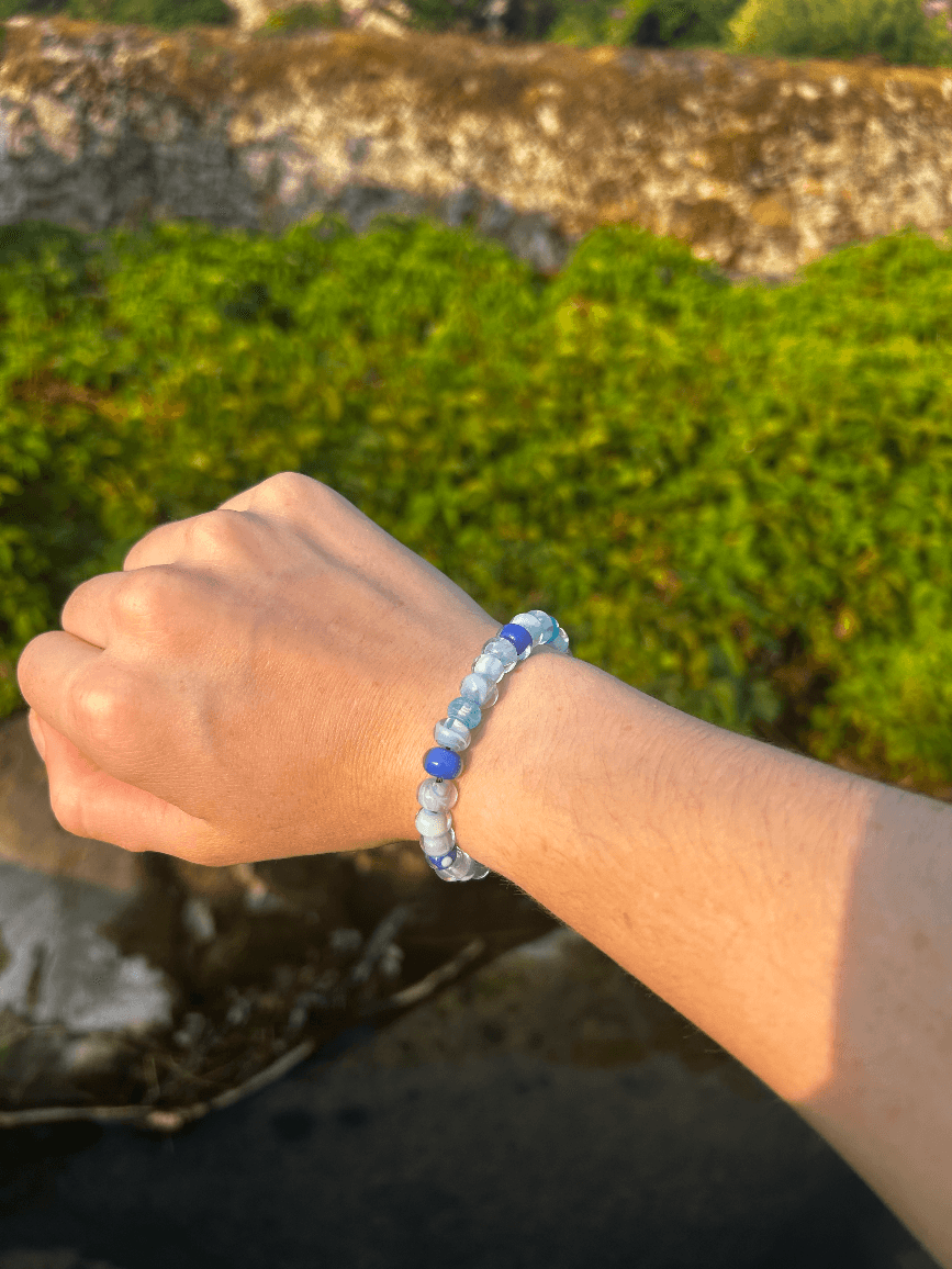Bracelet artisanal en perles de verre bleues et marbrées porté au poignet