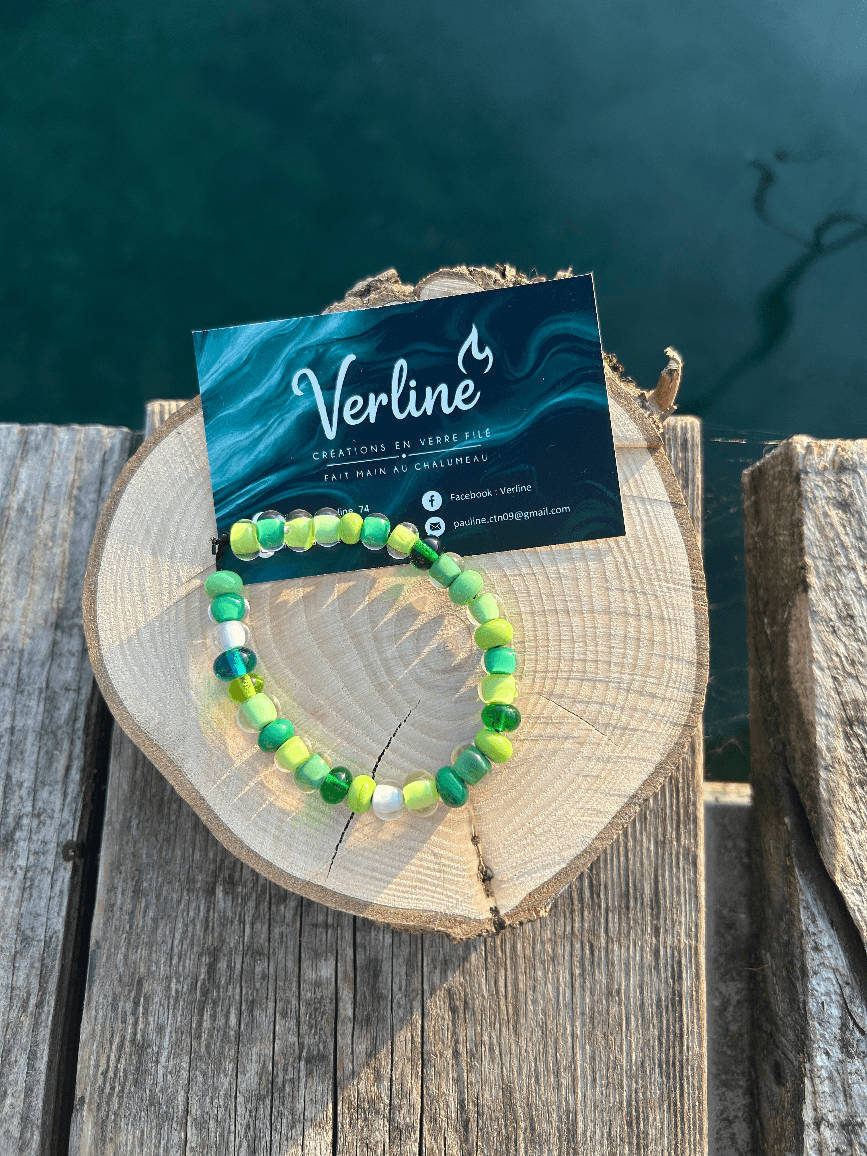 Bracelet composé de perles arrondies aux nuances de vert et perles transparentes sur une rondelle de bois.