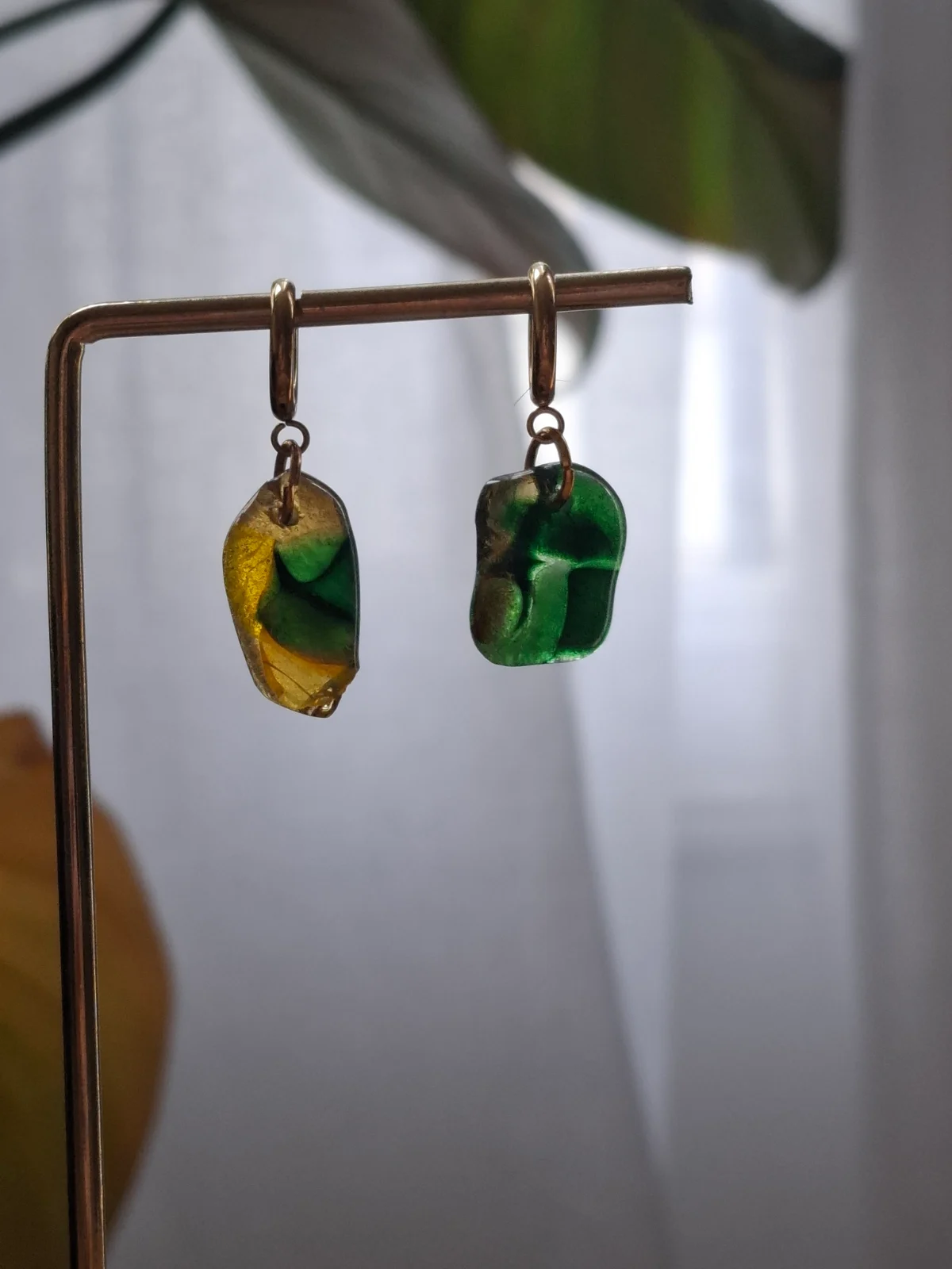 Paire de boucles d'oreilles pendantes en verre translucide vert et jaune sur un présentoir doré