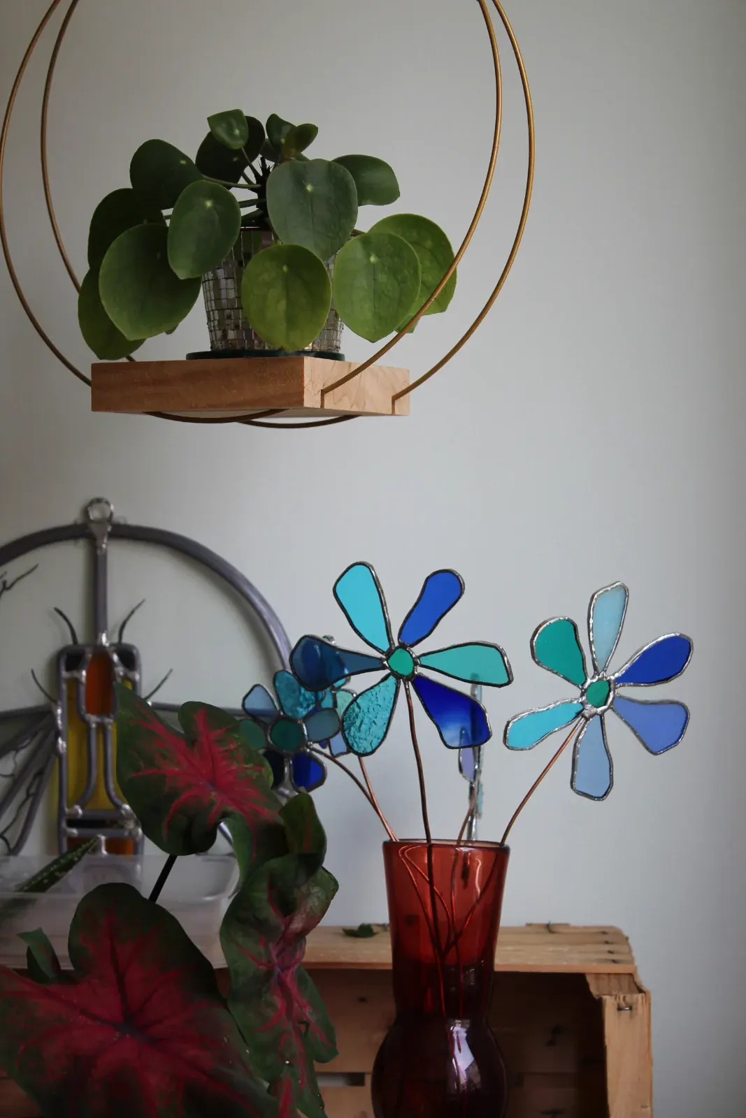 Fleurs stylisées en vitrail bleu sur tige en cuivre présentées dans un pré
