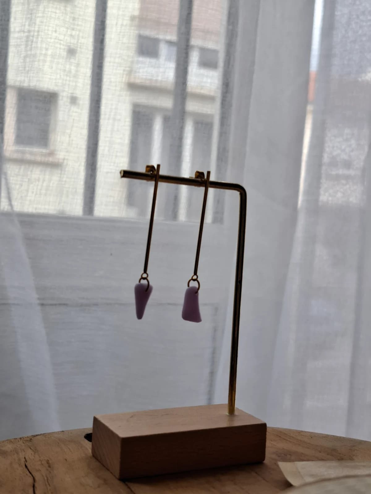 Boucles d'oreilles pendantes dorées avec pampilles violettes suspendues sur un support en métal.
