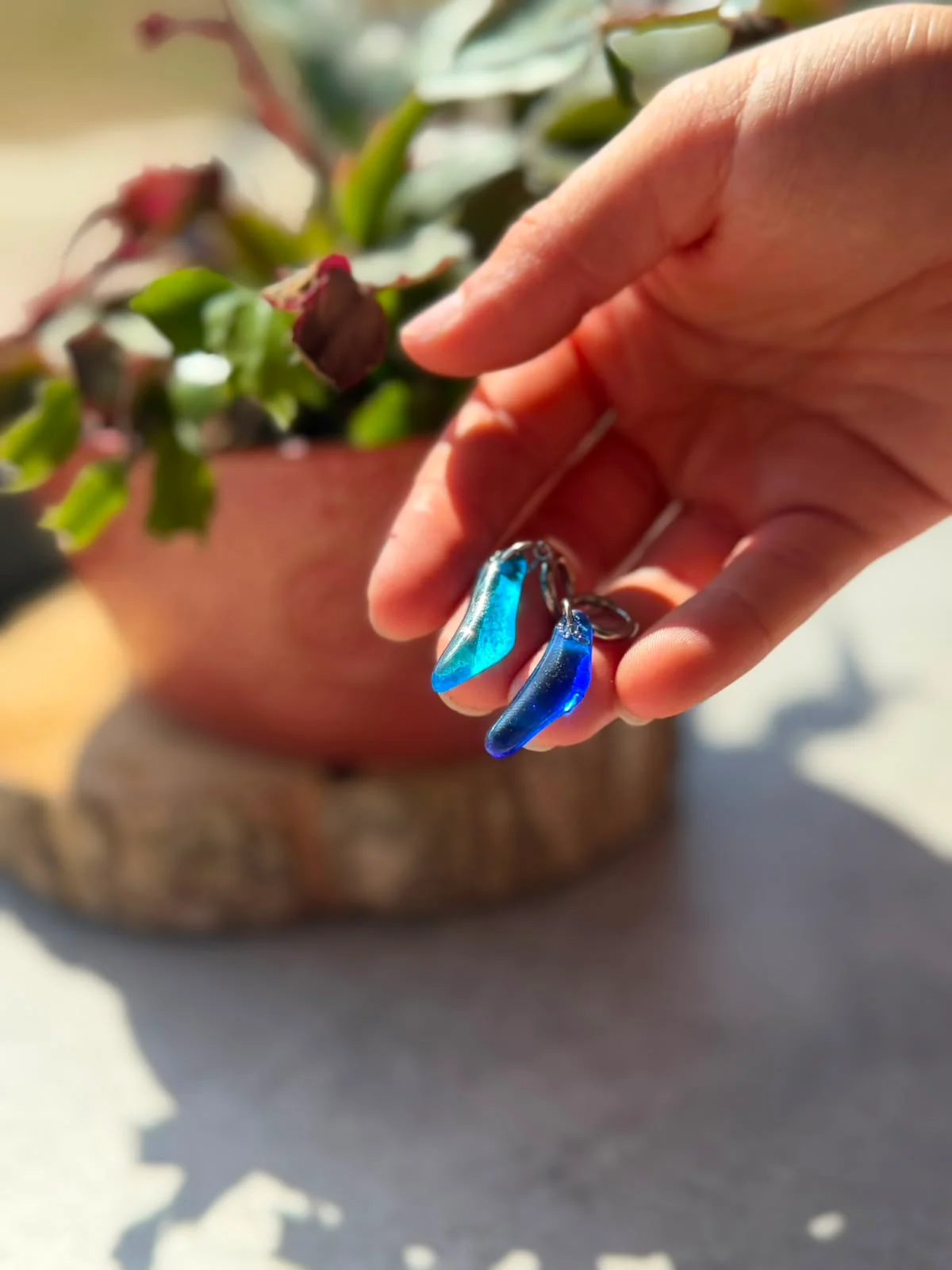 Boucles d'oreilles en verre bleu translucide tenues dans la paume d'une main.
