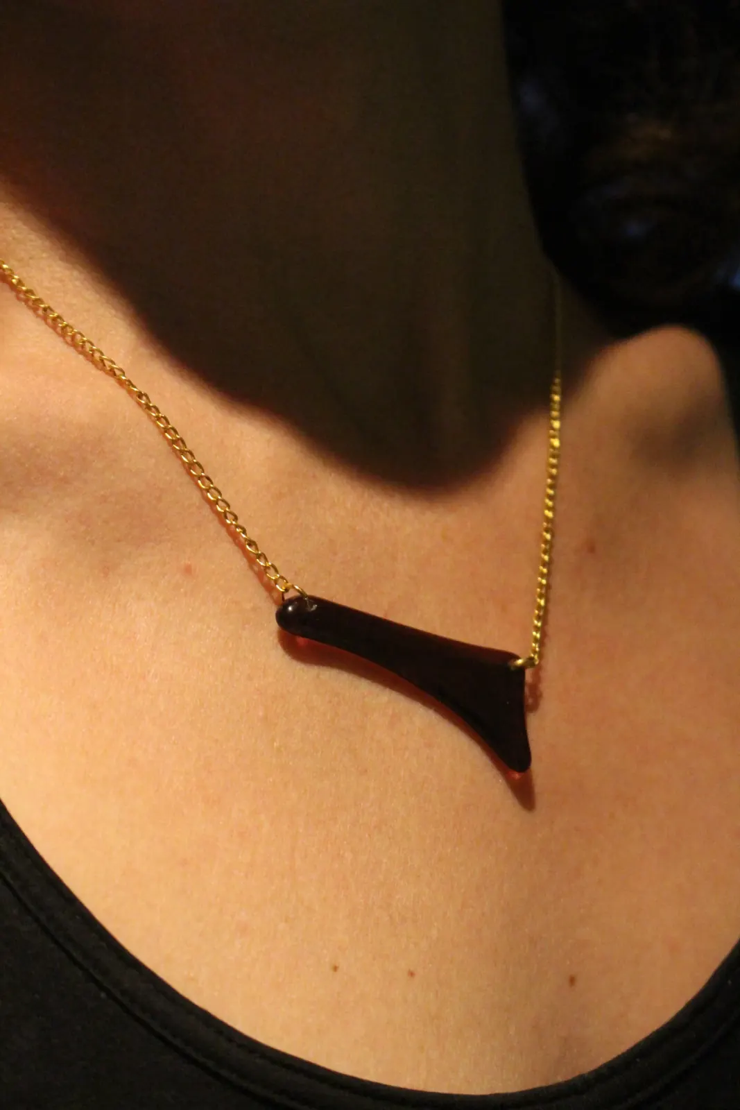 Collier graphique asymétrique porté au cou par une femme, vue de profil