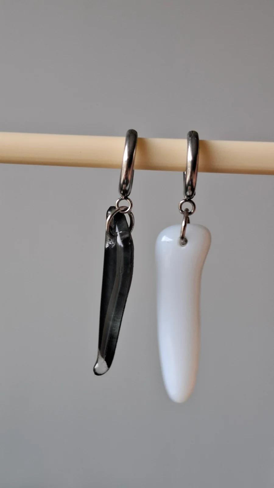 Dormeuses en acier suspendues avec un pendentif allongé noir et un blanc aux bords arrondis.