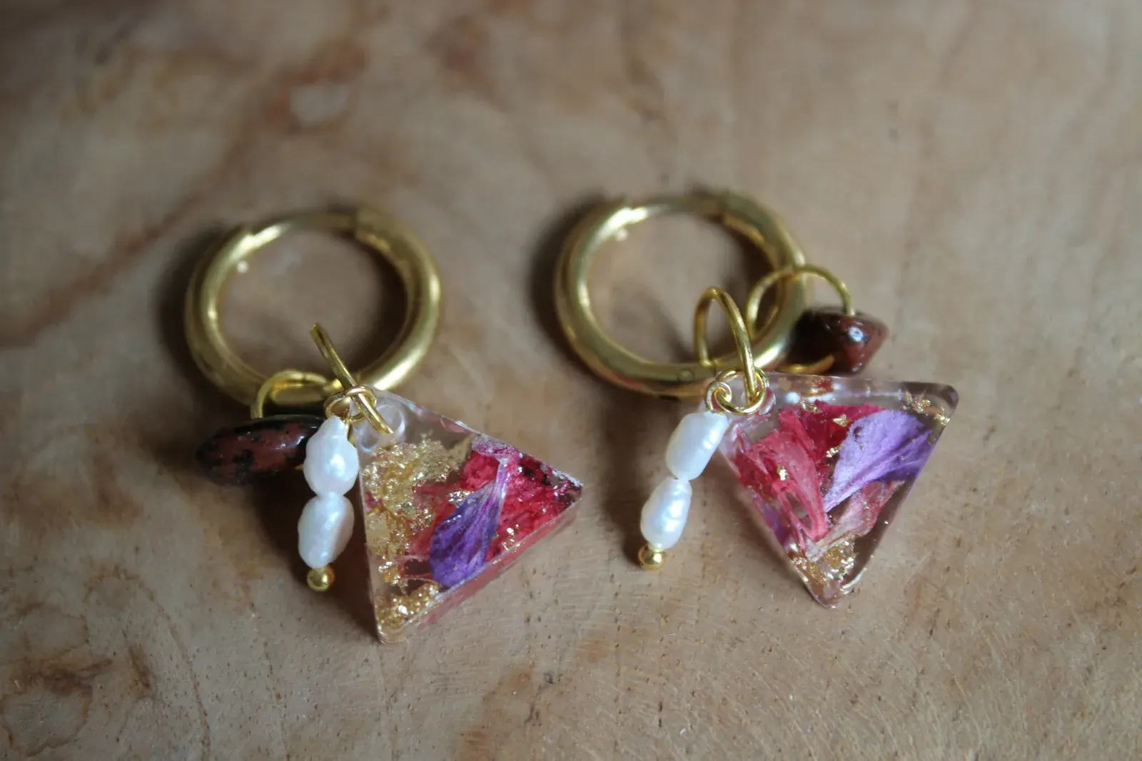 Gros plan sur les pendentifs triangulaires fleuris, feuilles d'or et petites perles d'eau douce.