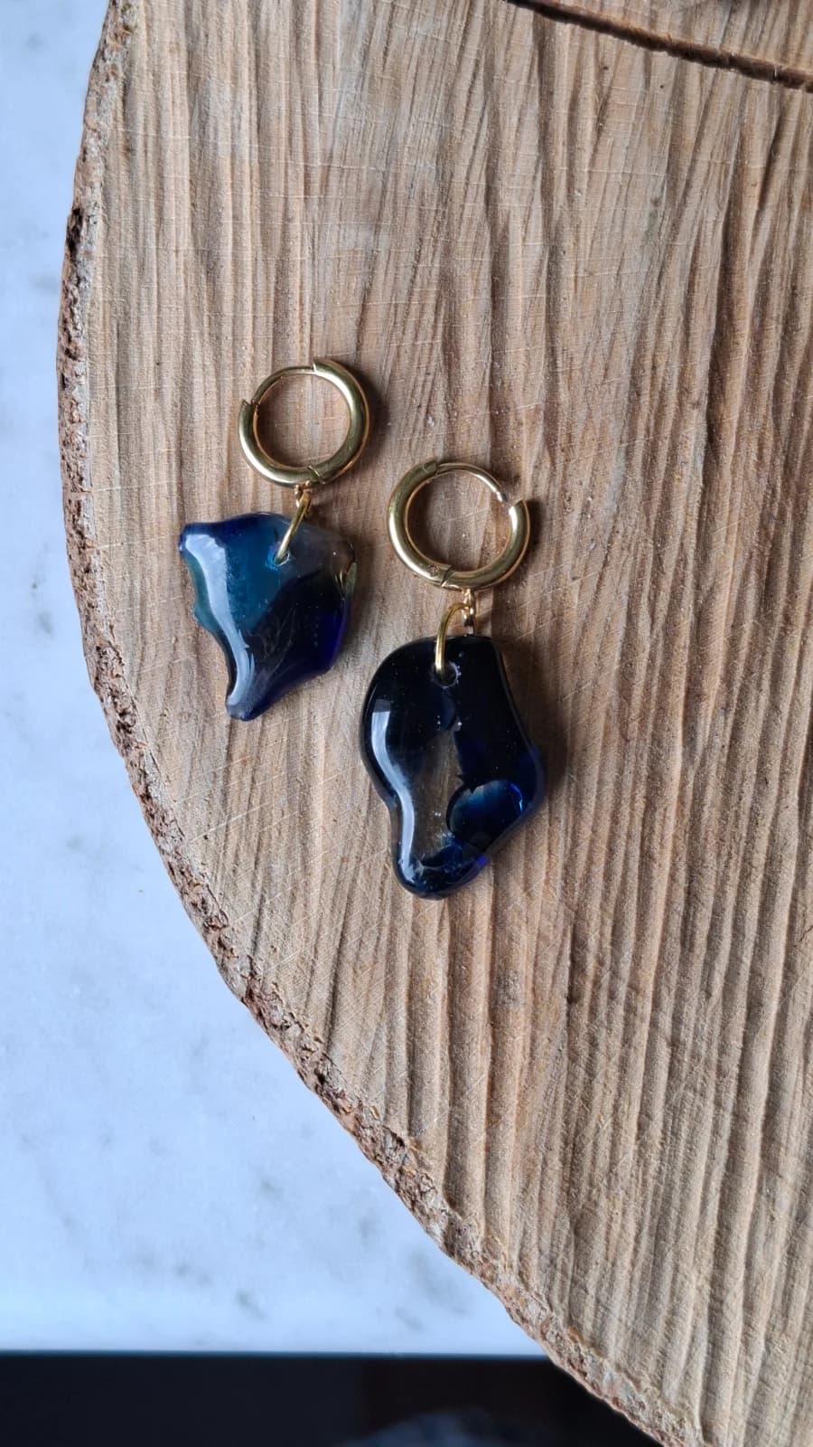Boucles d'oreilles pendantes en verre bleu et transparent aux formes asymétriques suspendues à une tige.