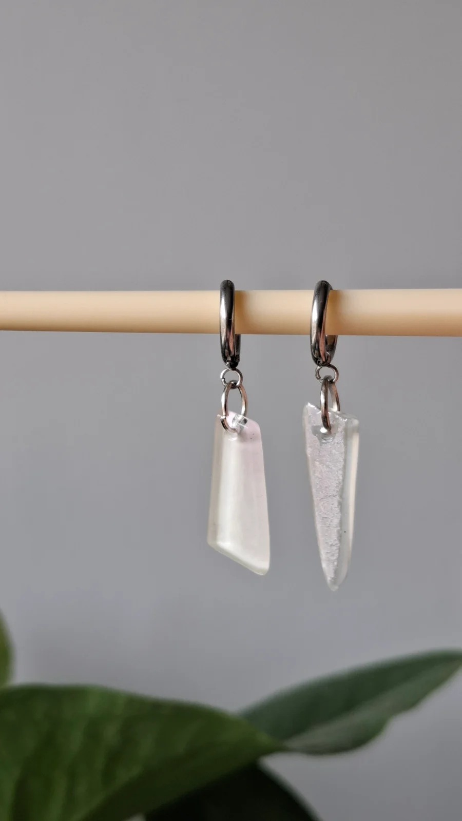 Détail suspendu des boucles d'oreilles pendantes en verre recyclé blanc laiteux.