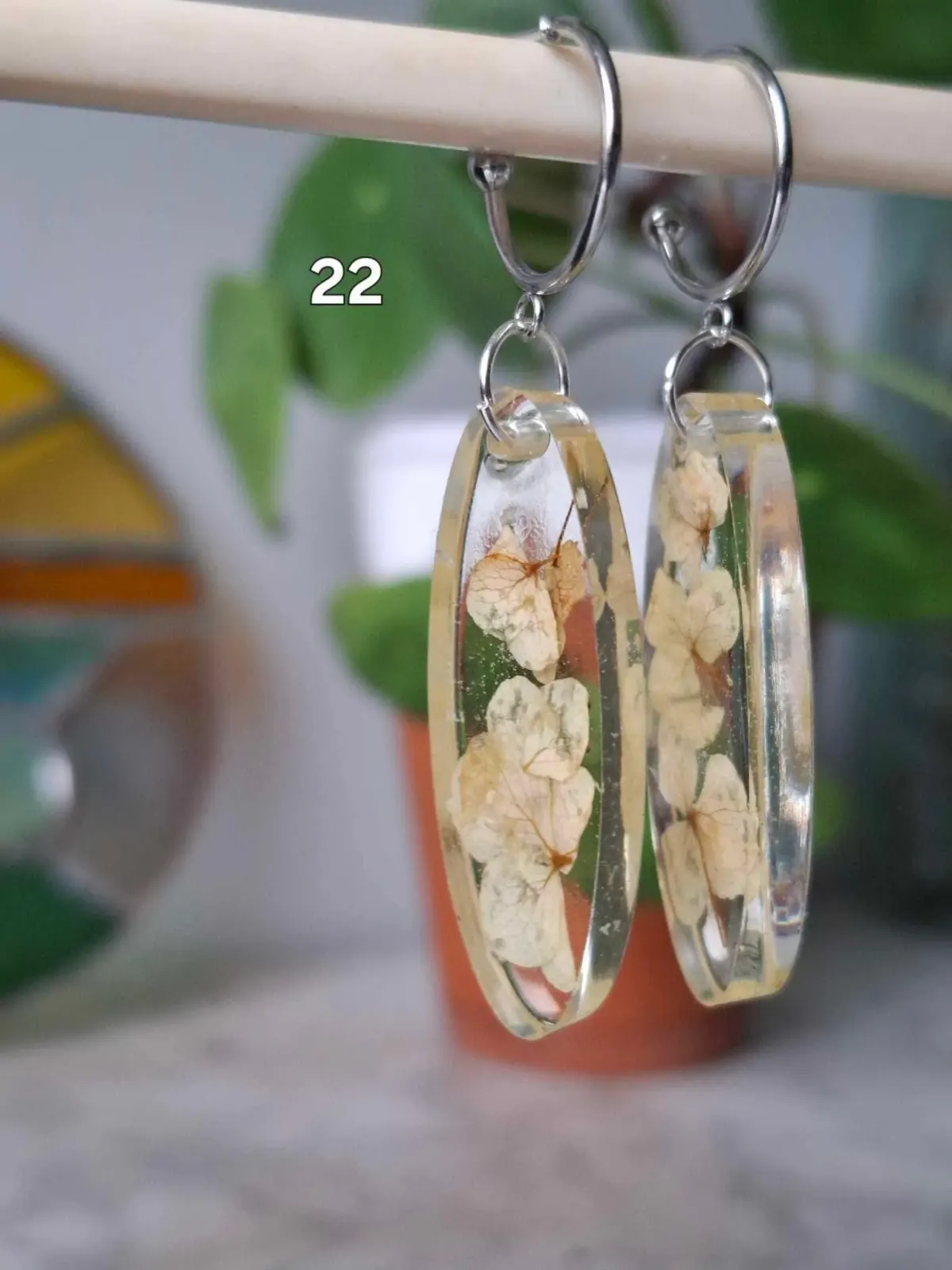 Boucles d'oreilles créoles avec pendentifs ovales transparents renfermant des fleurs séchées claires.