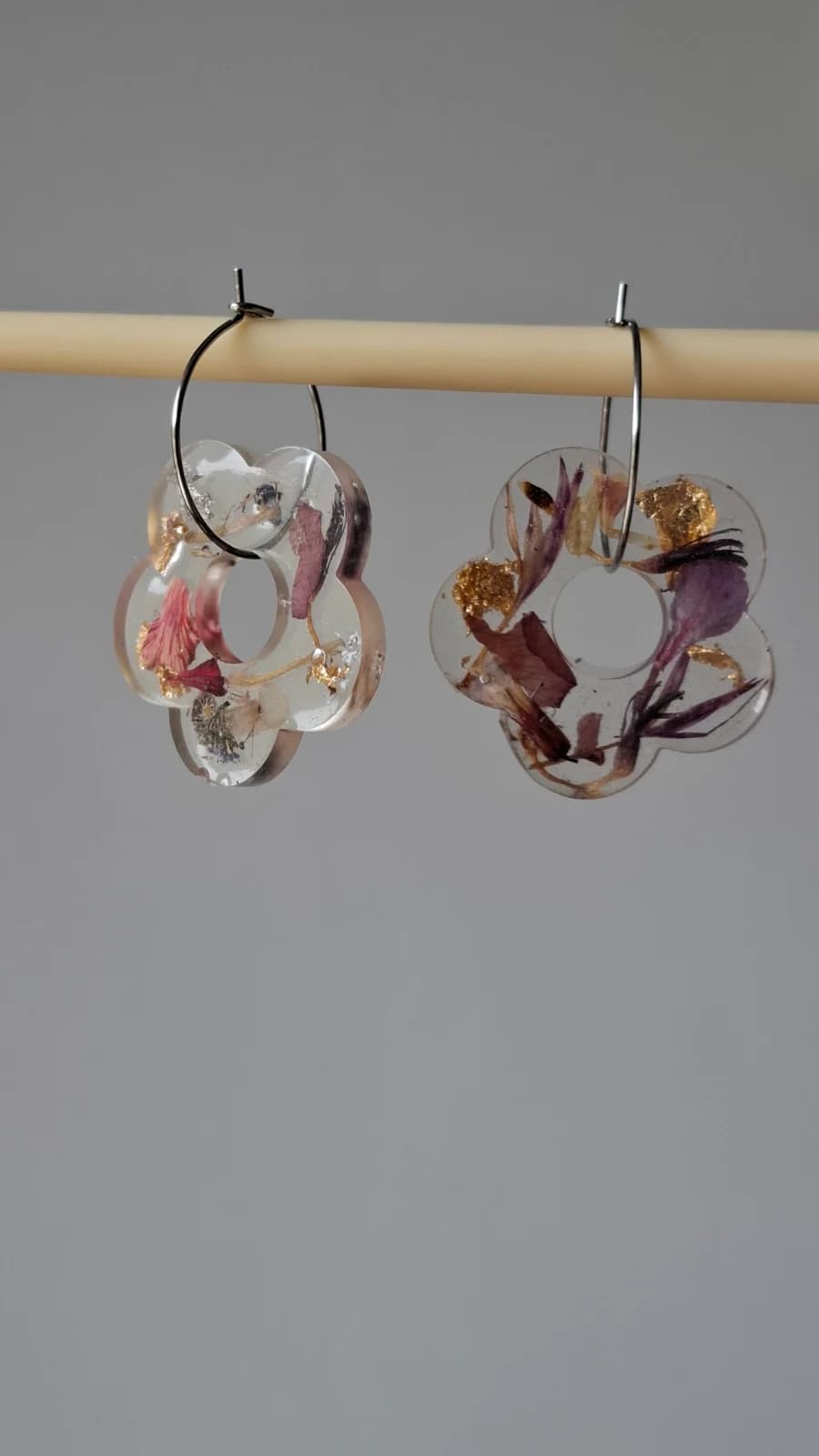Boucles d'oreilles créoles suspendues avec pendentifs floraux en résine et pétales séchés.