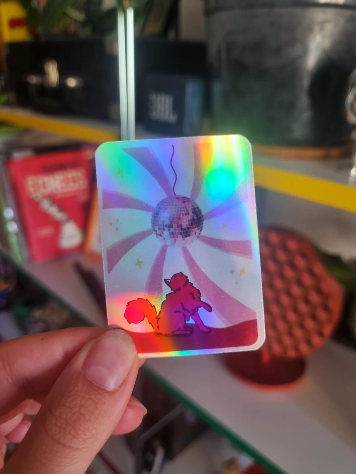 Sticker holographique rectangulaire illustrant un chat sous une boule à facettes disco et des rayons lumineux.
