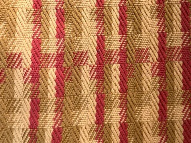 Gros plan sur le tissage géométrique artisanal en laine aux teintes or et terracotta