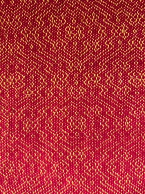 Gros plan sur le tissage artisanal rouge et jaune formant des motifs géométriques réguliers