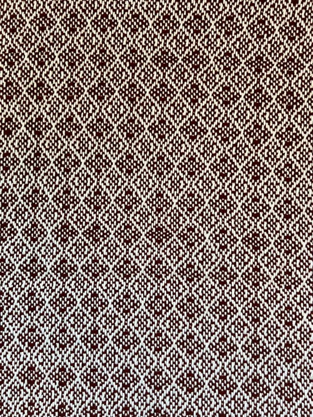 Gros plan sur le tissage géométrique bordeaux et blanc à motif de petits losanges