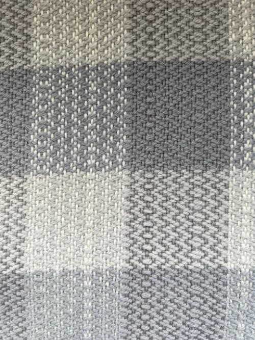 Gros plan sur le tissage artisanal à motifs géométriques gris et blancs