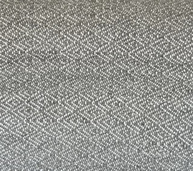 Gros plan sur les motifs géométriques du tissage artisanal en fils gris et blanc.