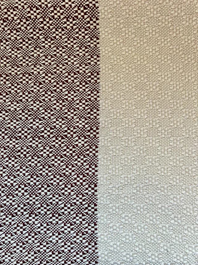 Gros plan sur le motif texturé du tissage bicolore bordeaux et beige clair.