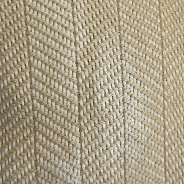 Gros plan sur le tissage artisanal à chevrons blanc et champagne d'une écharpe.