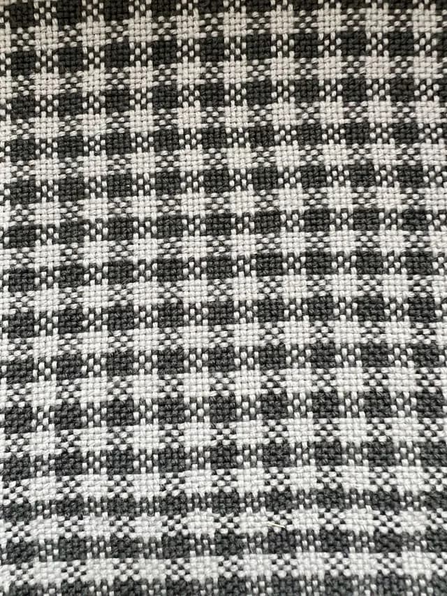 Gros plan sur le tissage artisanal géométrique bicolore noir et blanc de l'écharpe.