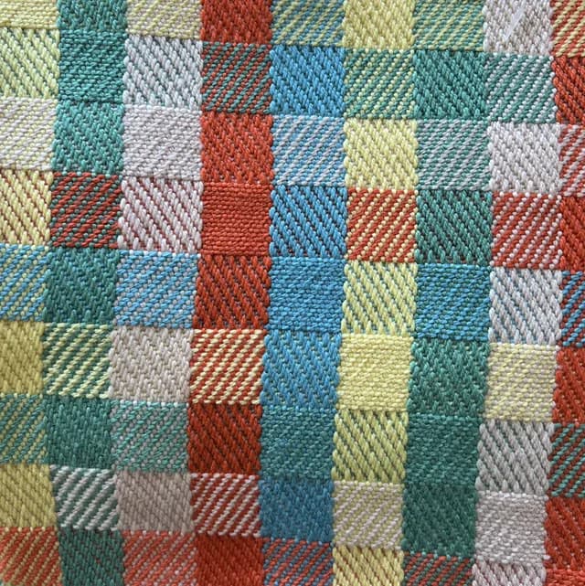 Gros plan sur le tissage artisanal à carreaux texturés multicolores en jaune, bleu, vert et terracotta.