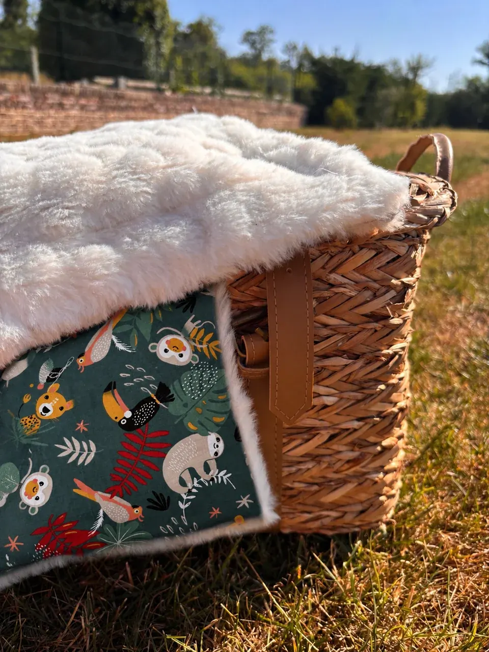 Couverture bébé à motifs jungle d'animaux et feuillage vert posée sur les barreaux d'un lit blanc