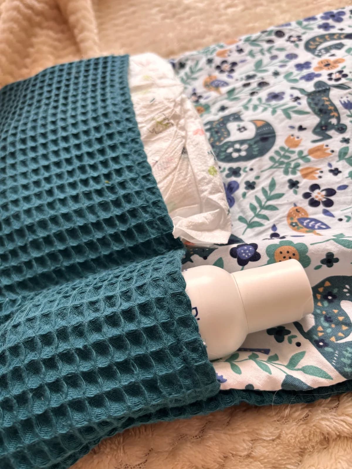 Tapis à langer déplié sur plaid beige avec accessoires assortis et panier de lingettes