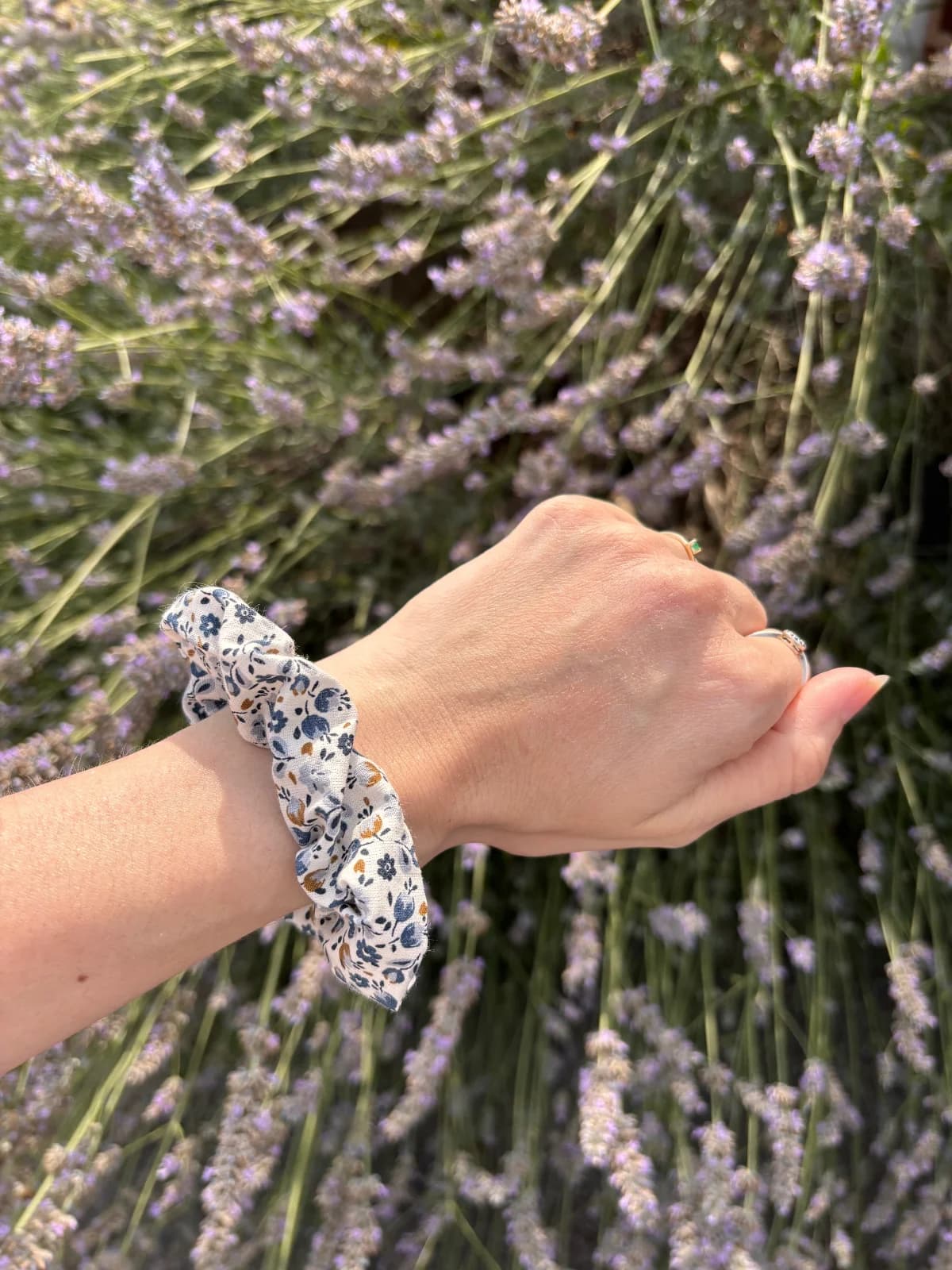 Chouchou fleuri bleu porté au poignet d'une main glissée dans la poche d'un jean denim.