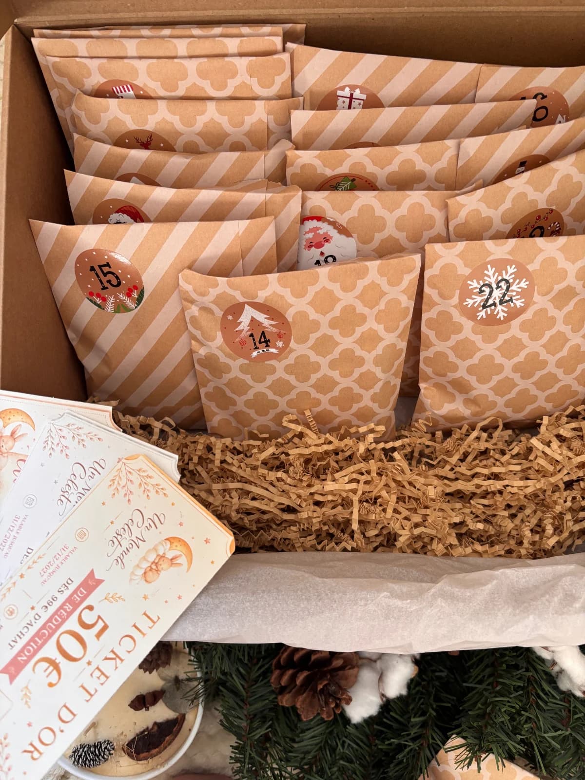 Pochettes numérotées en papier kraft présentées dans la boîte avec la carte Ticket d'Or au premier plan