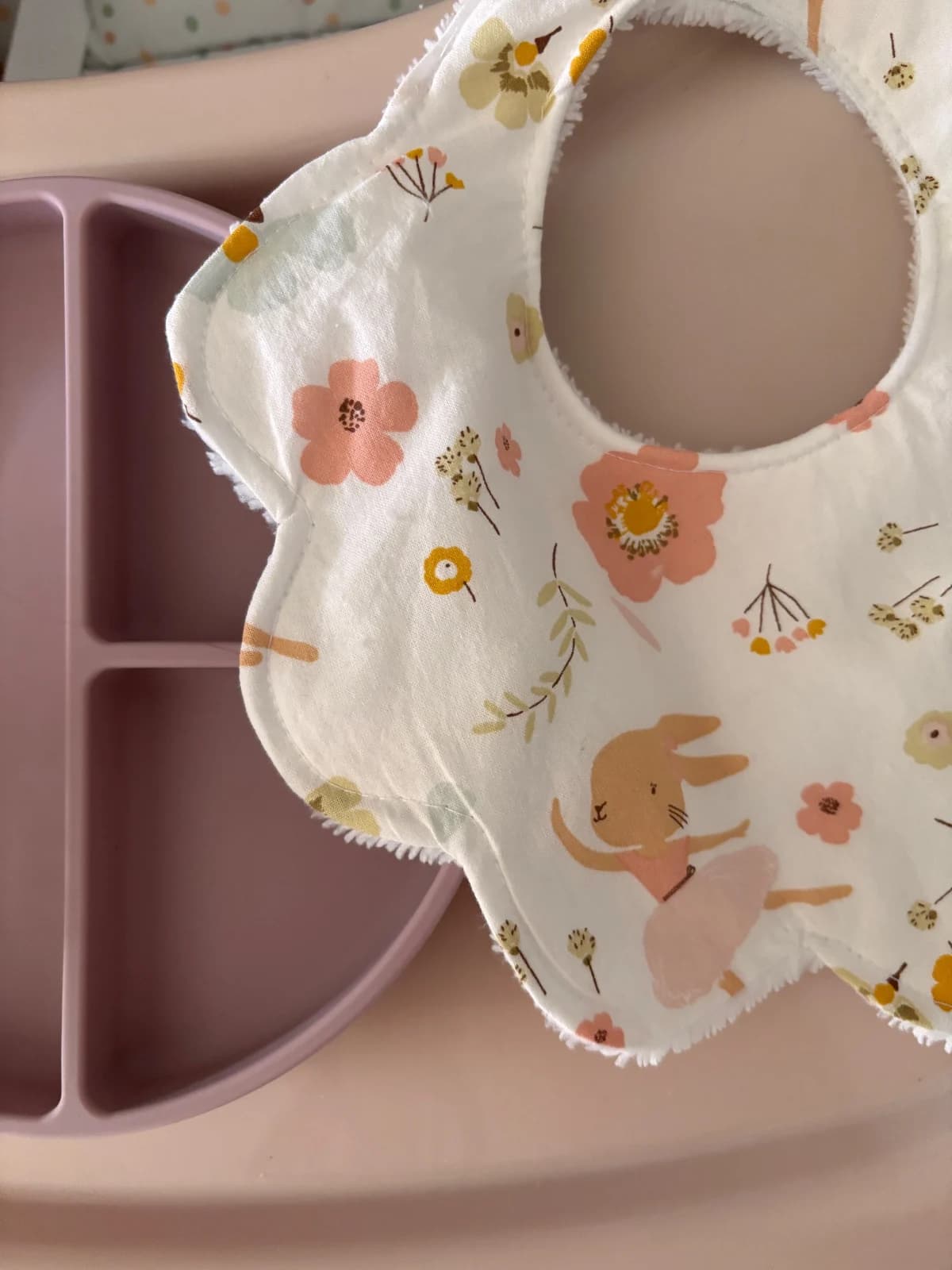 Détail du bavoir fleur montrant les imprimés de fleurs printanières et un petit lapin ballerine avec tutu rose.