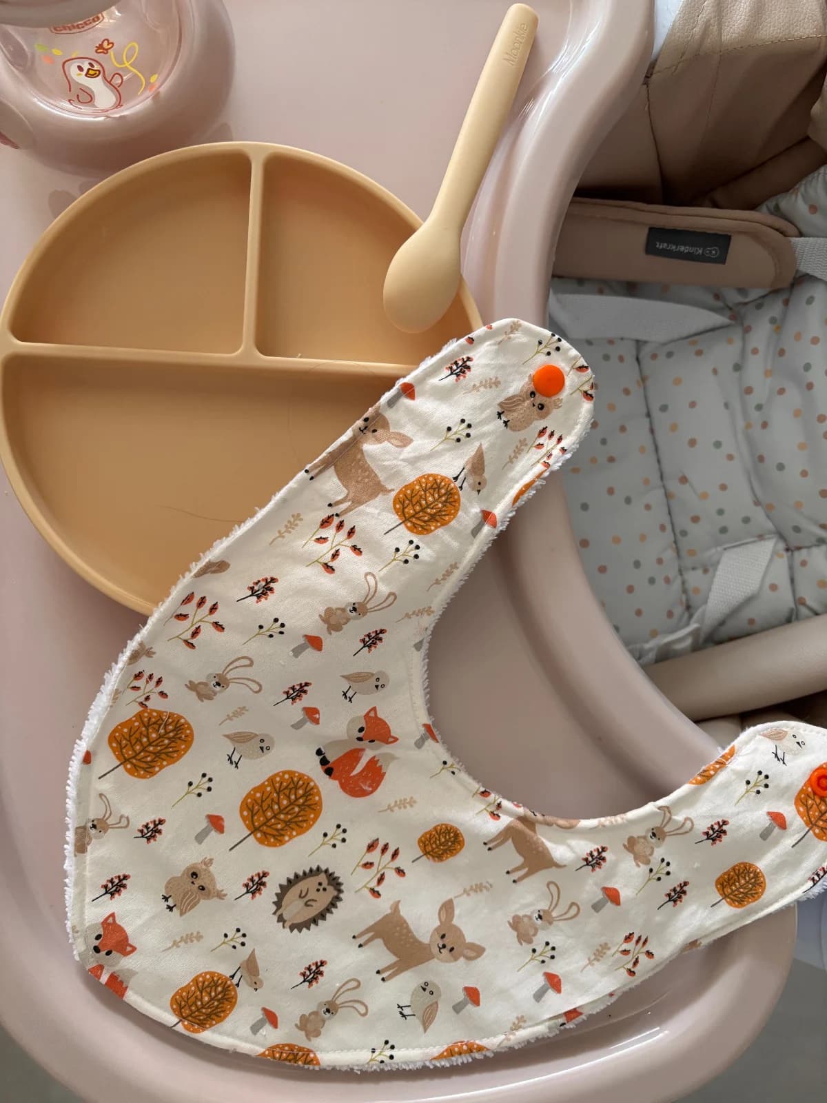 Vue de dessus du bavoir à bouton-pression motifs automne, présenté avec une assiette à compartiments.