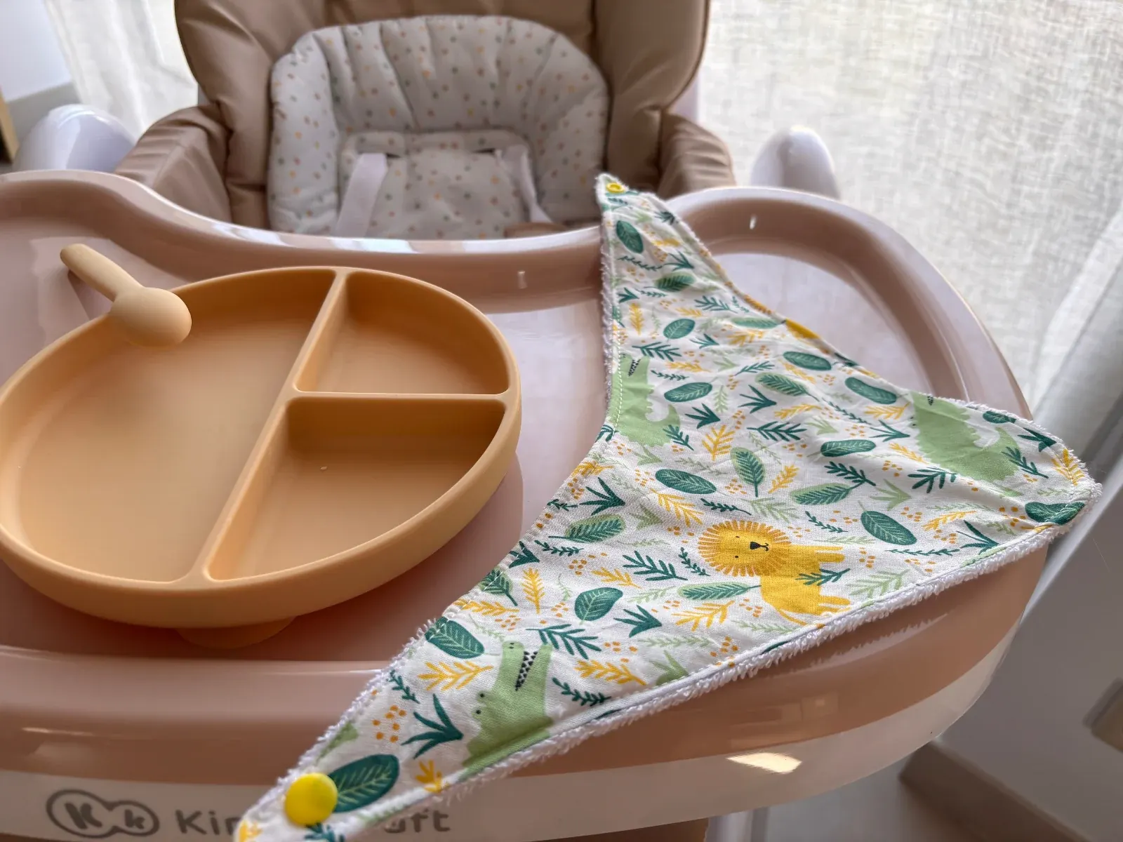Vue de dessus du bavoir bandana motif jungle avec lion et crocodile à côté d'une assiette compartimentée