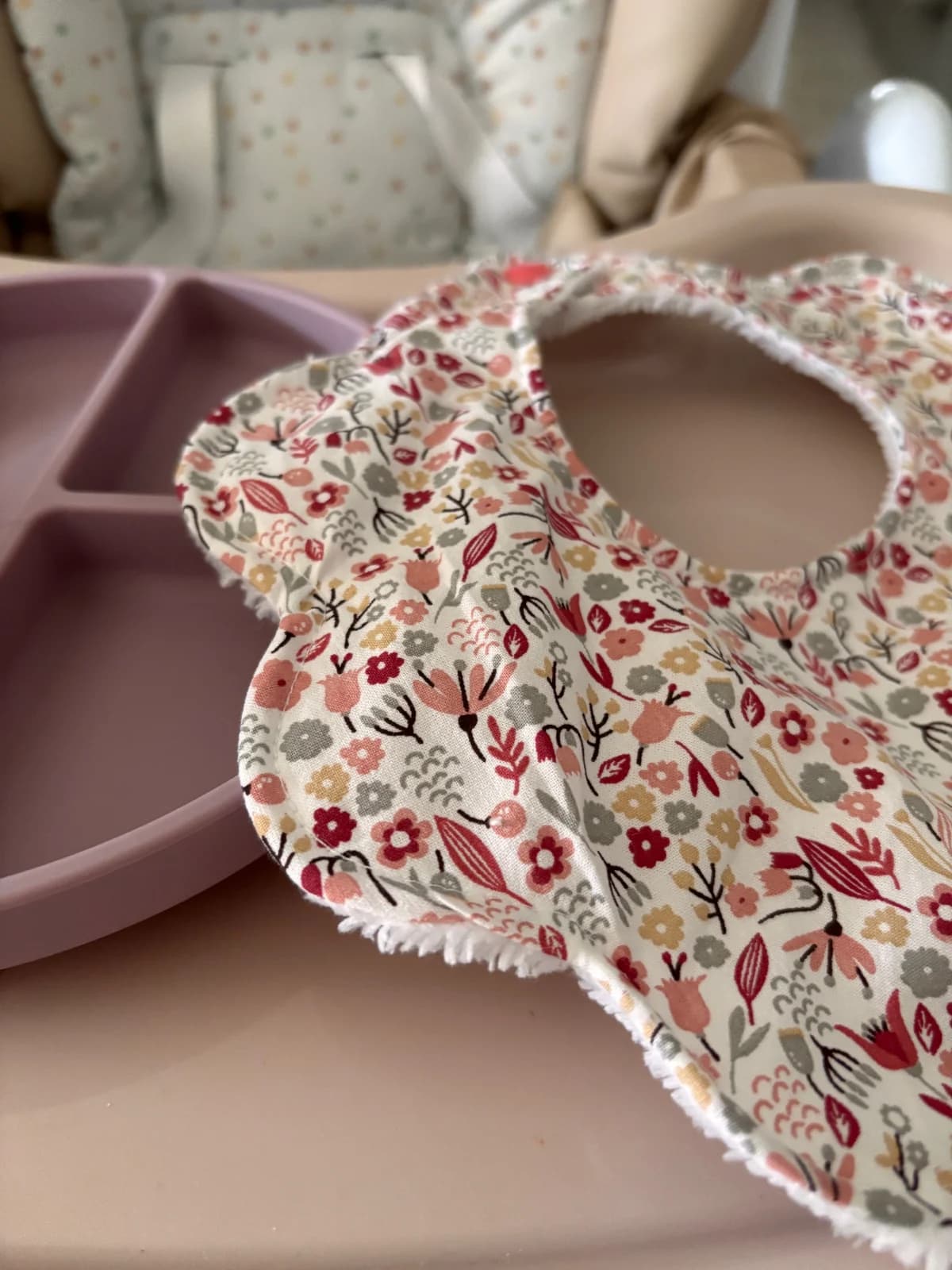 Gros plan sur les pétales arrondis en tissu à fleurs et la doublure en éponge blanche du bavoir