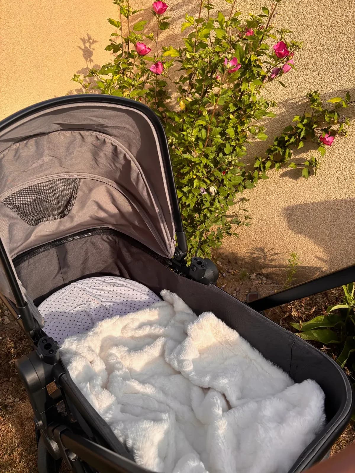 Couverture bébé moelleuse blanche installée dans la nacelle d'une poussette en extérieur