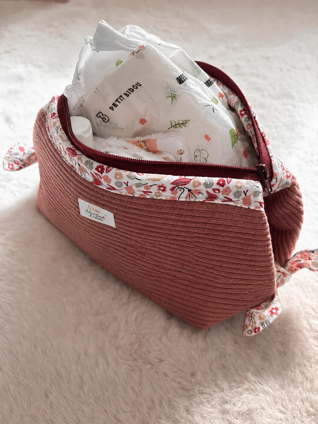 Gros plan sur le velours côtelé rose et le revers fleuri de la trousse de toilette