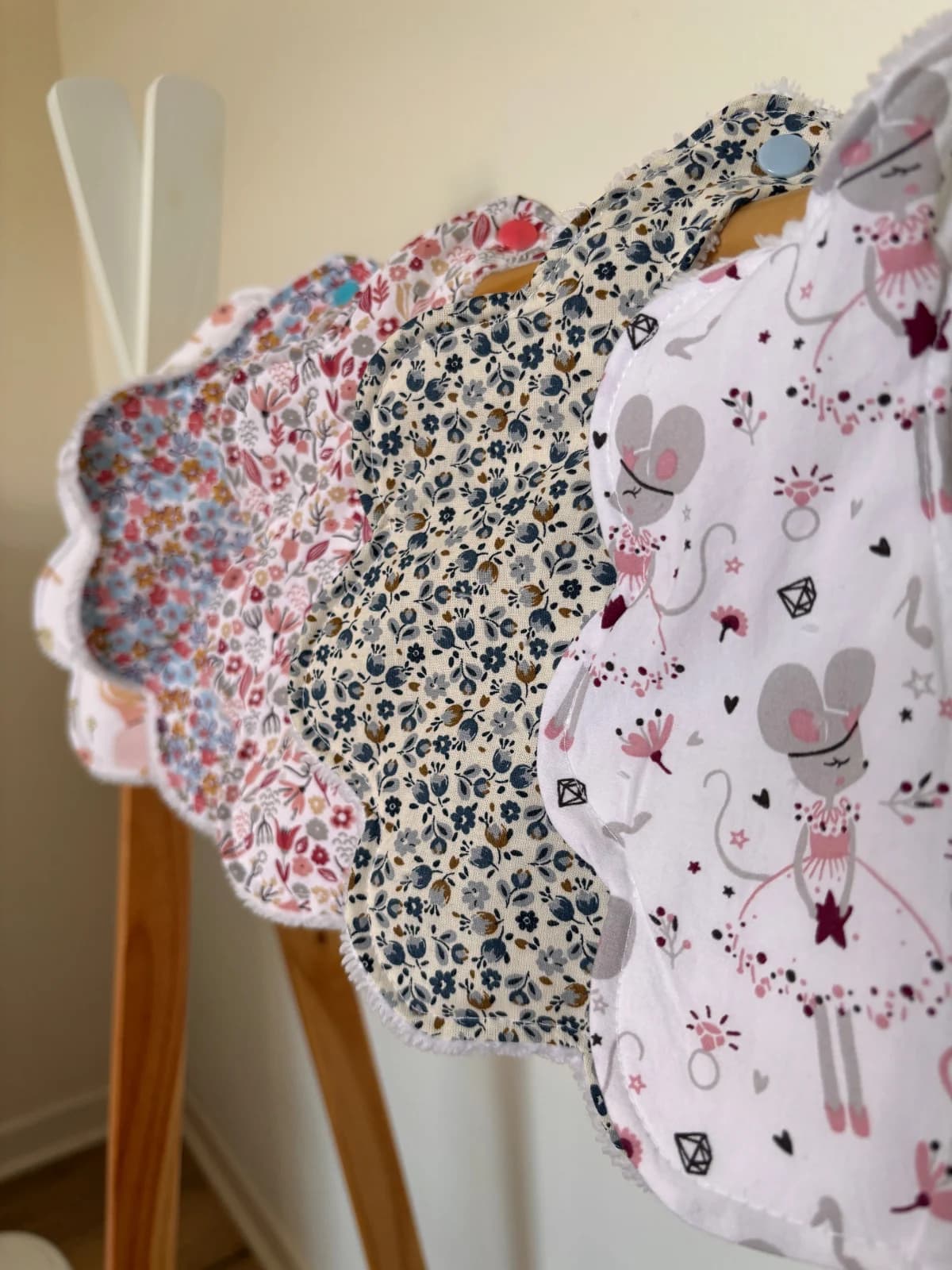 Bavoirs pour bébé en forme de fleur aux motifs fleuris et souris, suspendus sur un portant