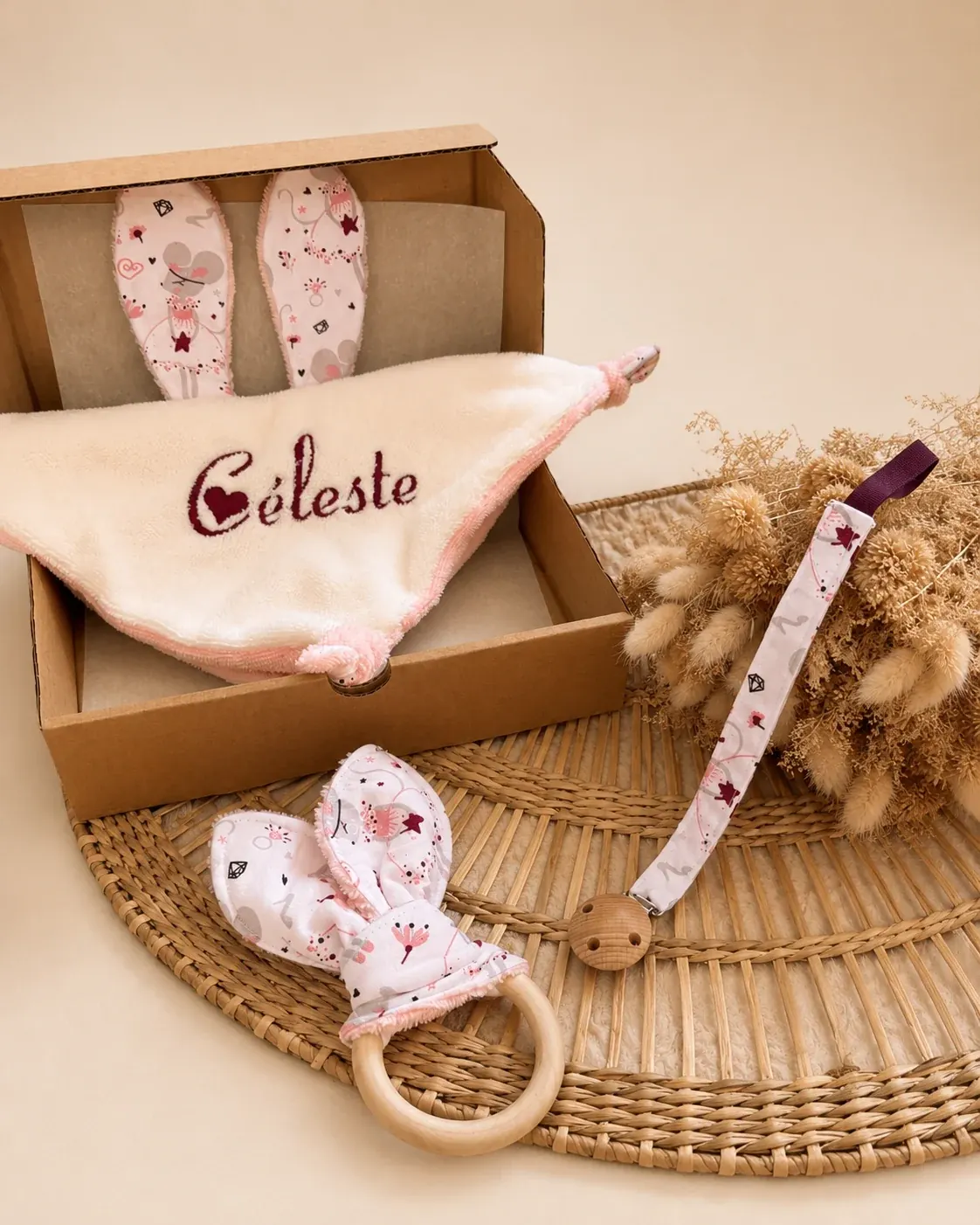Coffret en carton ouvert avec doudou brodé Céleste, anneau de dentition et attache-sucette assortis.