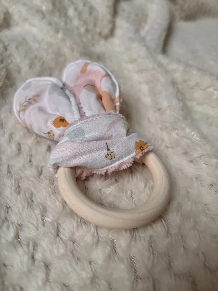 Gros plan sur l'anneau de dentition en bois lisse orné d'un tissu noué à motifs floraux.