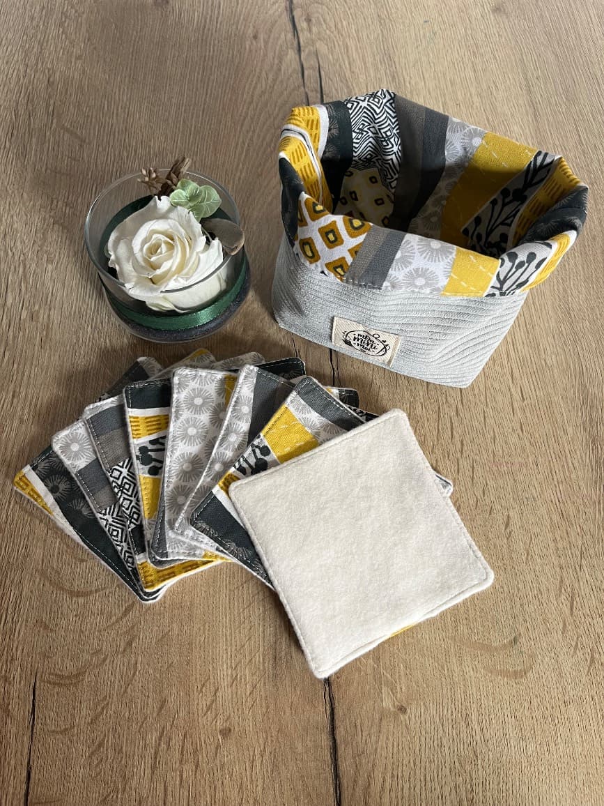 Panière en velours côtelé gris contenant les lingettes assorties, posée près d'une rose blanche.
