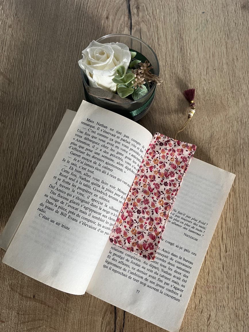 Marque-page en tissu à motif floral rose inséré au cœur d'un livre ouvert