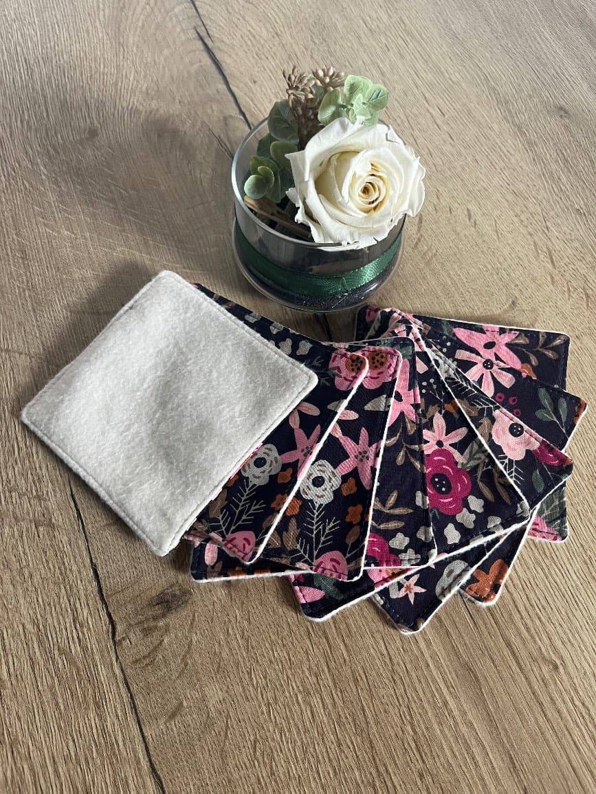 Panier en velours côtelé rose contenant les lingettes fleuries pliées à l'intérieur, posé sur une table.