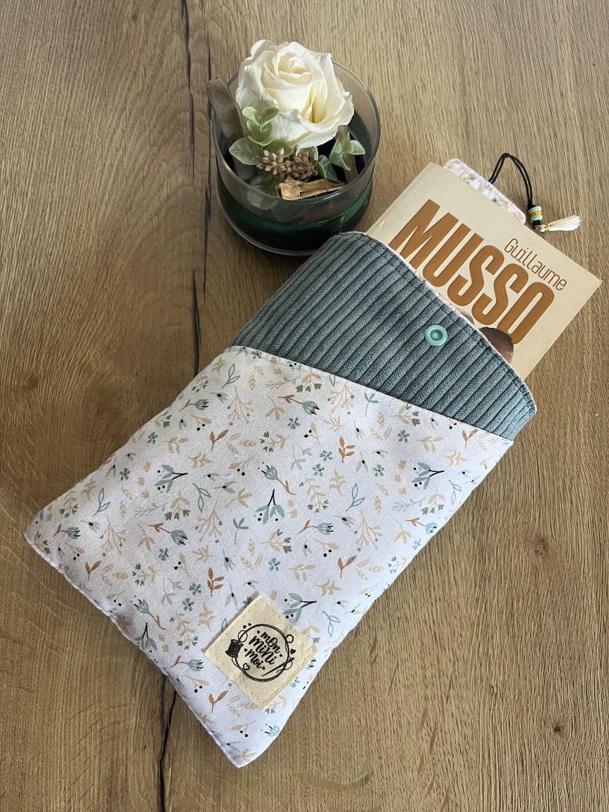 Livre de poche glissé dans la pochette ouverte en tissu fleuri et velours côtelé bleu jean.