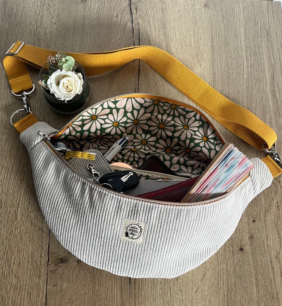 Intérieur du sac banane ouvert avec doublure fleurie rempli d'objets du quotidien.