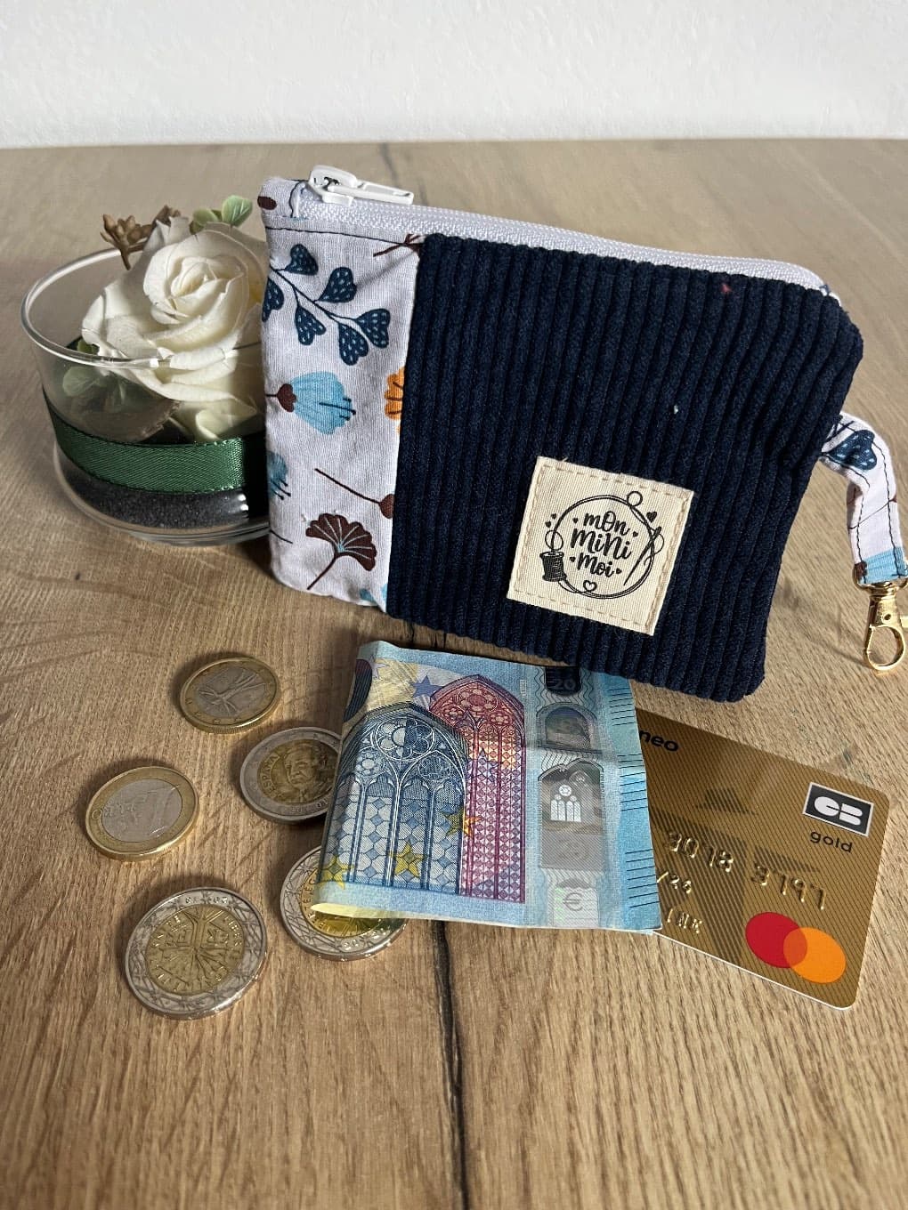 Porte-monnaie zippé en tissu côtelé bleu foncé et motif végétal avec étiquette de marque, monnaie et carte