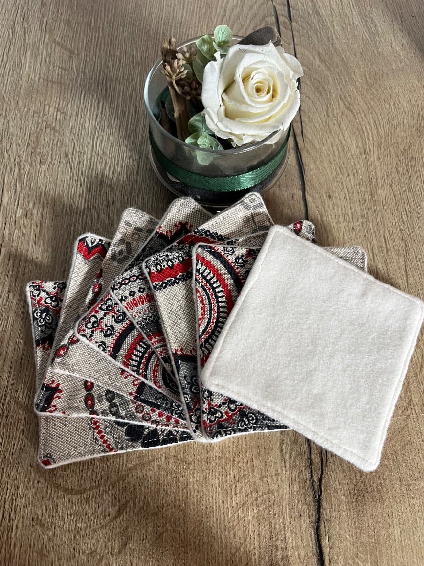 Éventail de lingettes carrées dévoilant les motifs circulaires rouges et noirs et la face en molleton blanc.