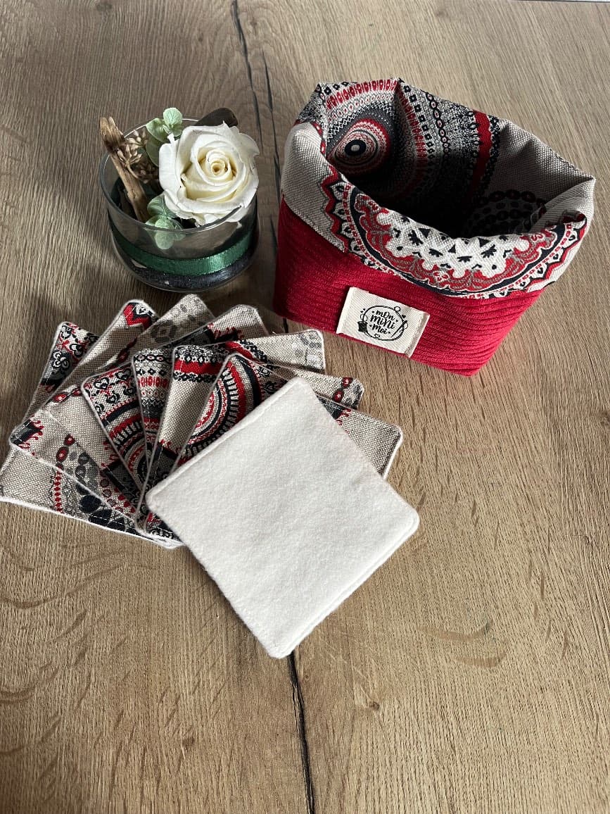 Panier souple en tissu côtelé rouge à doublure imprimée et ses lingettes carrées posées à plat sur une table.