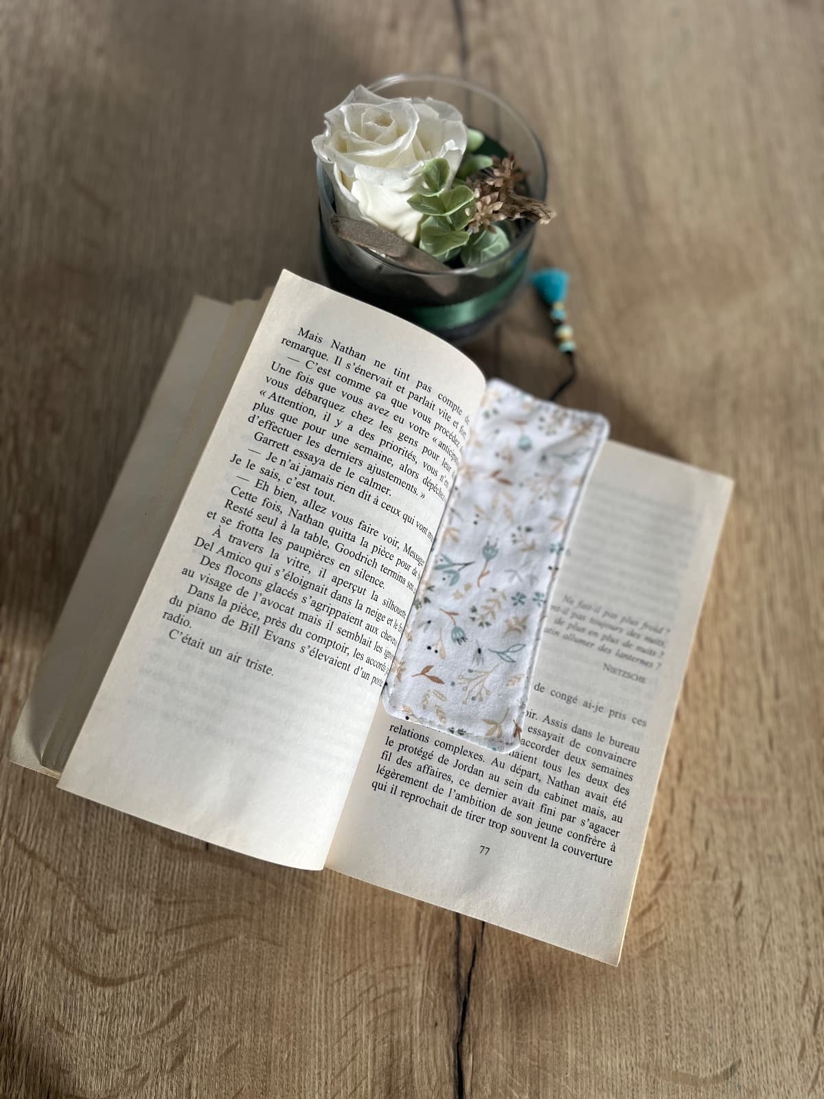 Marque-page glissé dans un livre fermé avec son pompon bleu dépassant en haut