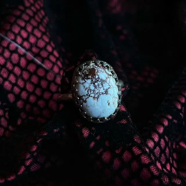 Gros plan sur la pierre blanche marbrée de brun d'une bague artisanale sertie d'argent.