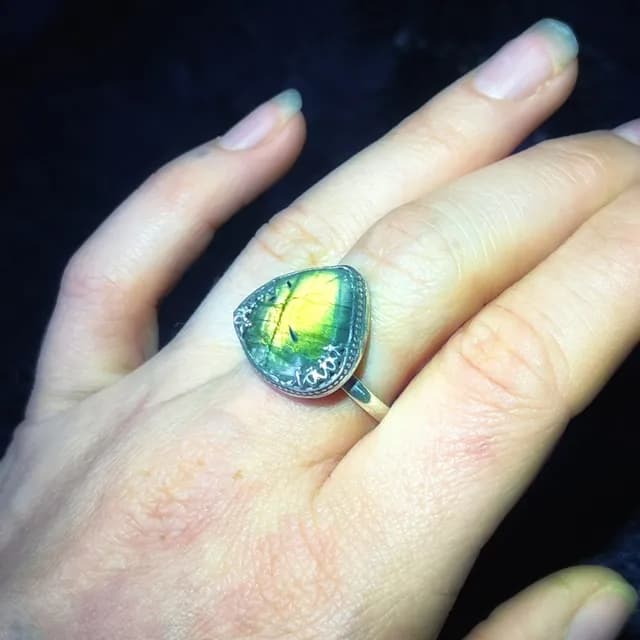 Bague en argent et labradorite naturelle triangle portée à la main avec reflets jaunes et verts