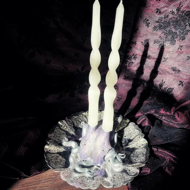 Vue du dessus du bougeoir montrant le réceptacle sculpté, les bougies torsadées et la base violette.