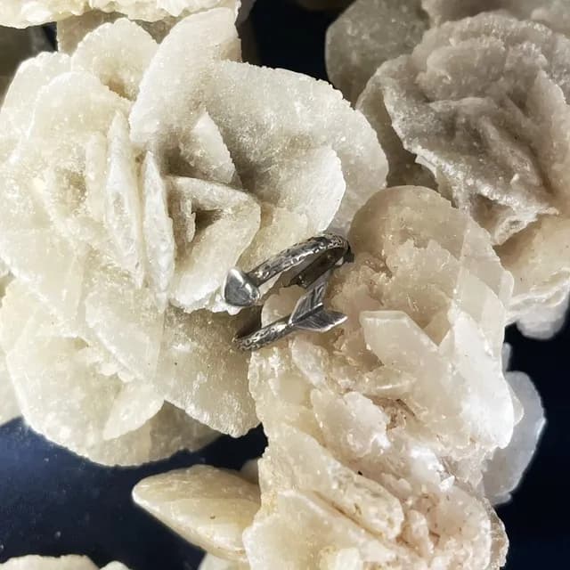 Bague ouverte gravée avec extrémité en cœur et pointe de flèche sur rose des sables.