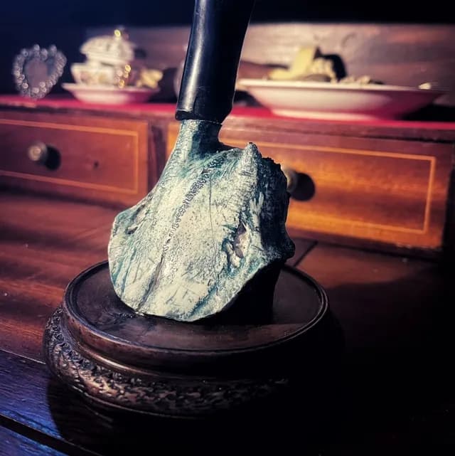 Détail de la base vert et blanc du bougeoir reposant sur un socle en bois verni.